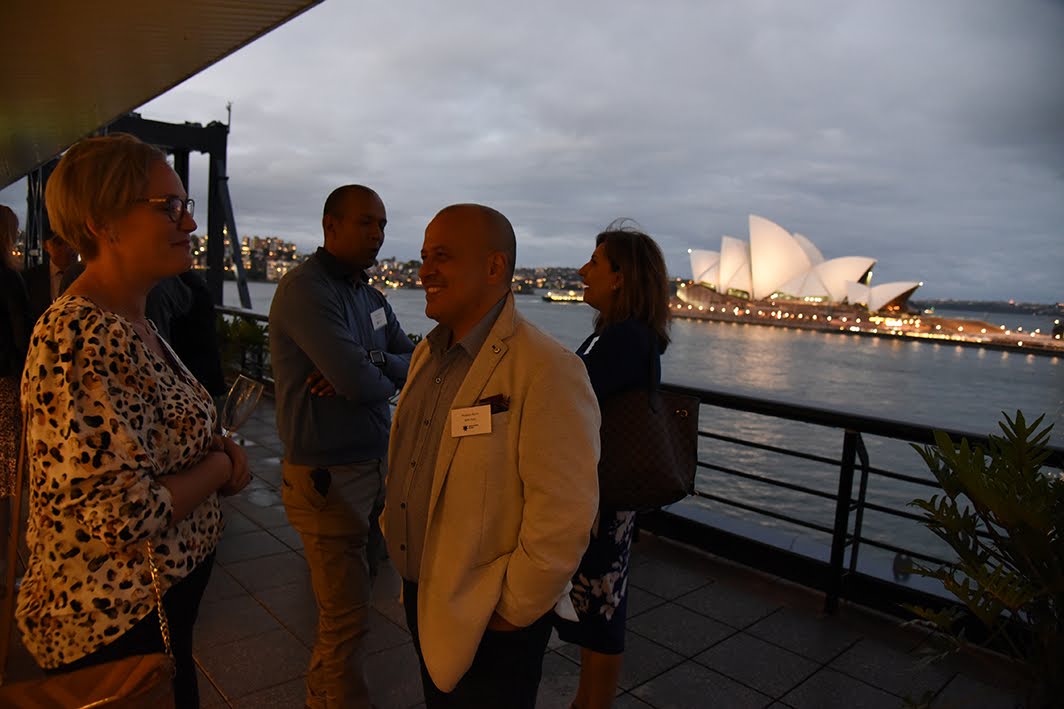 people talking in pairs with opera house in background